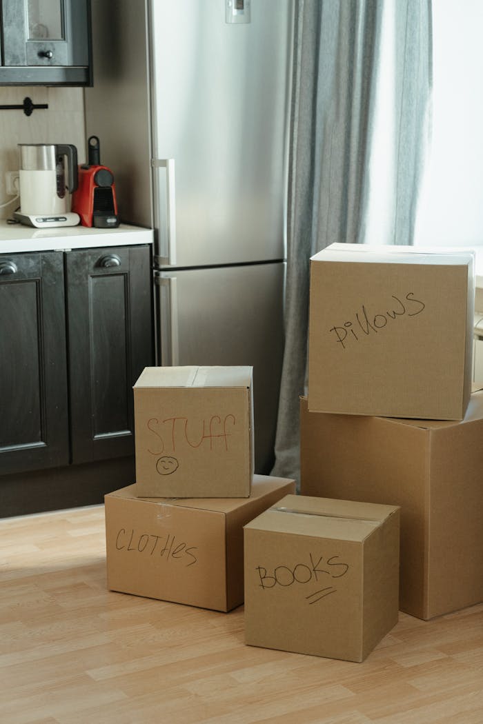 Cardboard boxes labeled with contents in a kitchen, suggesting a recent move-in.